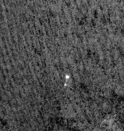 The NASA Phoenix spaceship, dangling from its parachute system, swoops toward a perilous but successful landing in the frigid polar plains of Mars, a moment in time and space caught by the telescopic High Resolution Imaging Science Experiment (HiRISE) camera on another NASA spacecraft, the Mars Reconnaissance Orbiter, flying far overhead. Photo: NASA